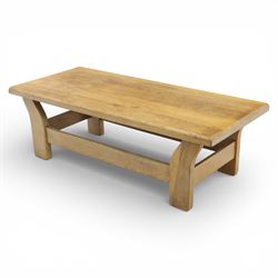 Modern oak coffee table, rectangular solid top with softly rounded edges, raised on shaped slab end supports united by a full-width stretcher