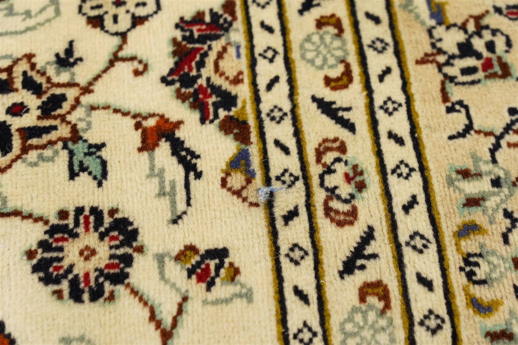 Central Persian Kashan hand-knotted carpet, ivory field with central lobed medallion issuing an all-over design of scrolling vines, palmettes, and floral sprays, within conforming spandrels, enclosed by a foliate border, framed by multiped guard stripes, with cotton fringe ends 