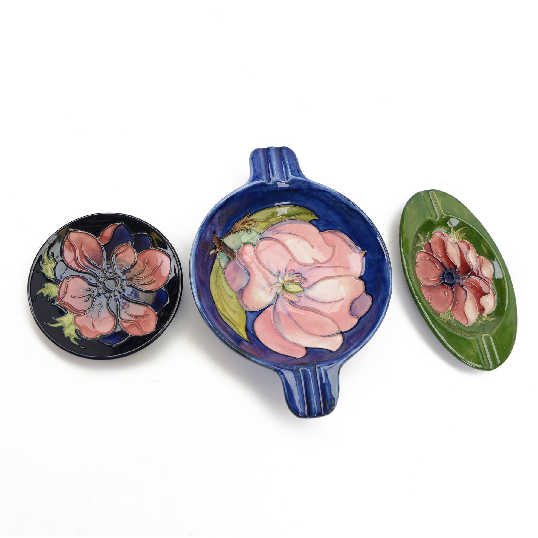 Two Moorcroft ashtrays in Magnolia pattern and Anemone pattern, together with pin dish in anemone pattern  