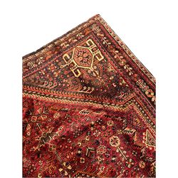 Persian Qashqai red ground rug, the main field decorated profusely with small stylised motifs, central lozenge medallion, multi-band border decorated with trailing foliate and flower head motifs 