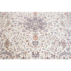 Persian ivory ground Kashan carpet, the busy field decorated with a central floral pole medallion with matching spandrels, the field profusely decorated with scrolling foliate motifs, the crimson guard stripe with repeating scrolling palmettes