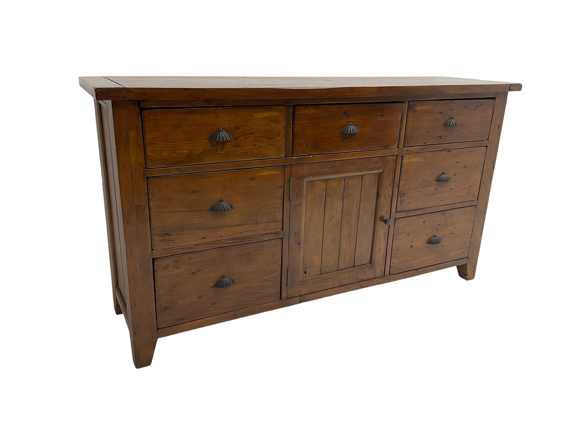 Stained pine rustic sideboard, rectangular top over seven drawers and single panelled cupboard, fitted with shell handles