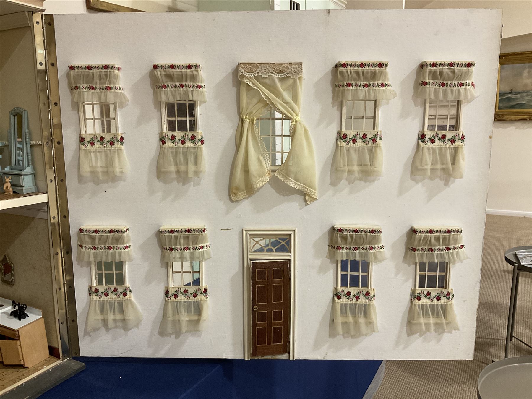 Kit-built wooden dolls house, possibly by Honeychurch, as a 19th century style double fronted two-storey residence; with stucco walls and flat roof with circular skylight and parapet with balusters; central door with fanlight, Corinthium columns and balcony over; simulated sash windows to three sides; hinged front facade opening to reveal a partially furnished interior with central hall, stairs and landing, two ground floor rooms and two first floor en suite bedrooms; wired for electric lighting W69cm H70cm D41cm