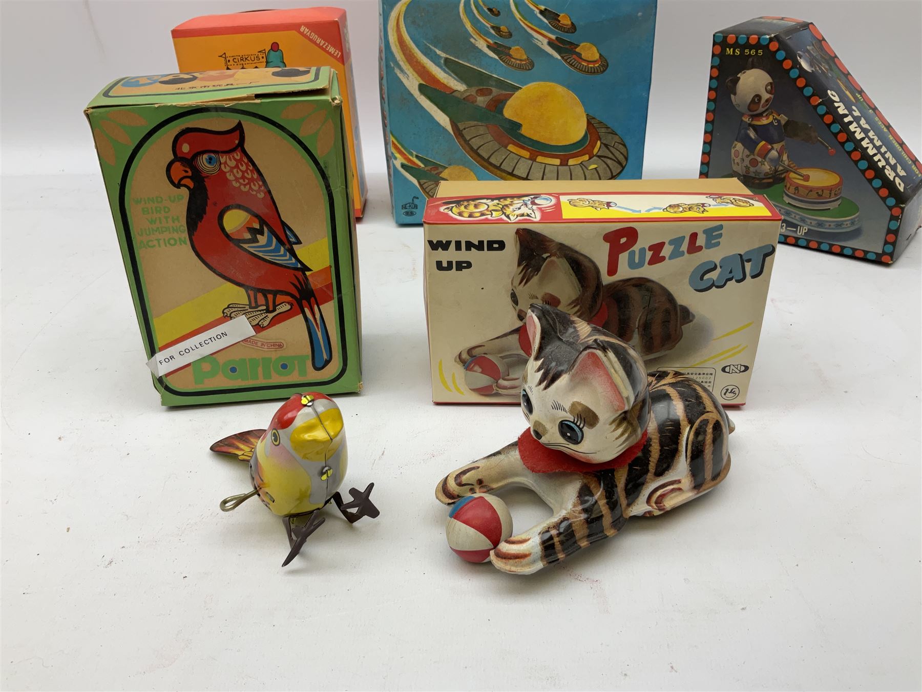 Seven modern Chinese, Japanese and Continental boxed tin-plate toys including Ucan Daire Flying Saucer, Drumming Animal, Circus Clown, Puzzle Cat, Bird with Jumping Action etc; and a quantity of clockwork toy keys (7)