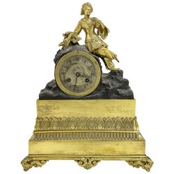 French early 19th century 8-day mantle clock, with a gilt figure of a  Turkish lady resting on a drum enclosed Parisian movement, on a broad decorated plinth resting on scroll feet, silvered dial with Roman numerals and steel moon hands, with a silk suspension and count wheel striking movement, striking the hours on a bell.
