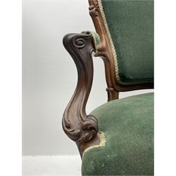 Set three Victorian rosewood drawing room open armchairs, shaped and moulded frames carved with scrolls, the arms with scrolled terminals and shaped foliate carved supports, upholstered in green velvet, serpentine sprung seats, the cabriole supports carved with flower heads terminating at castors