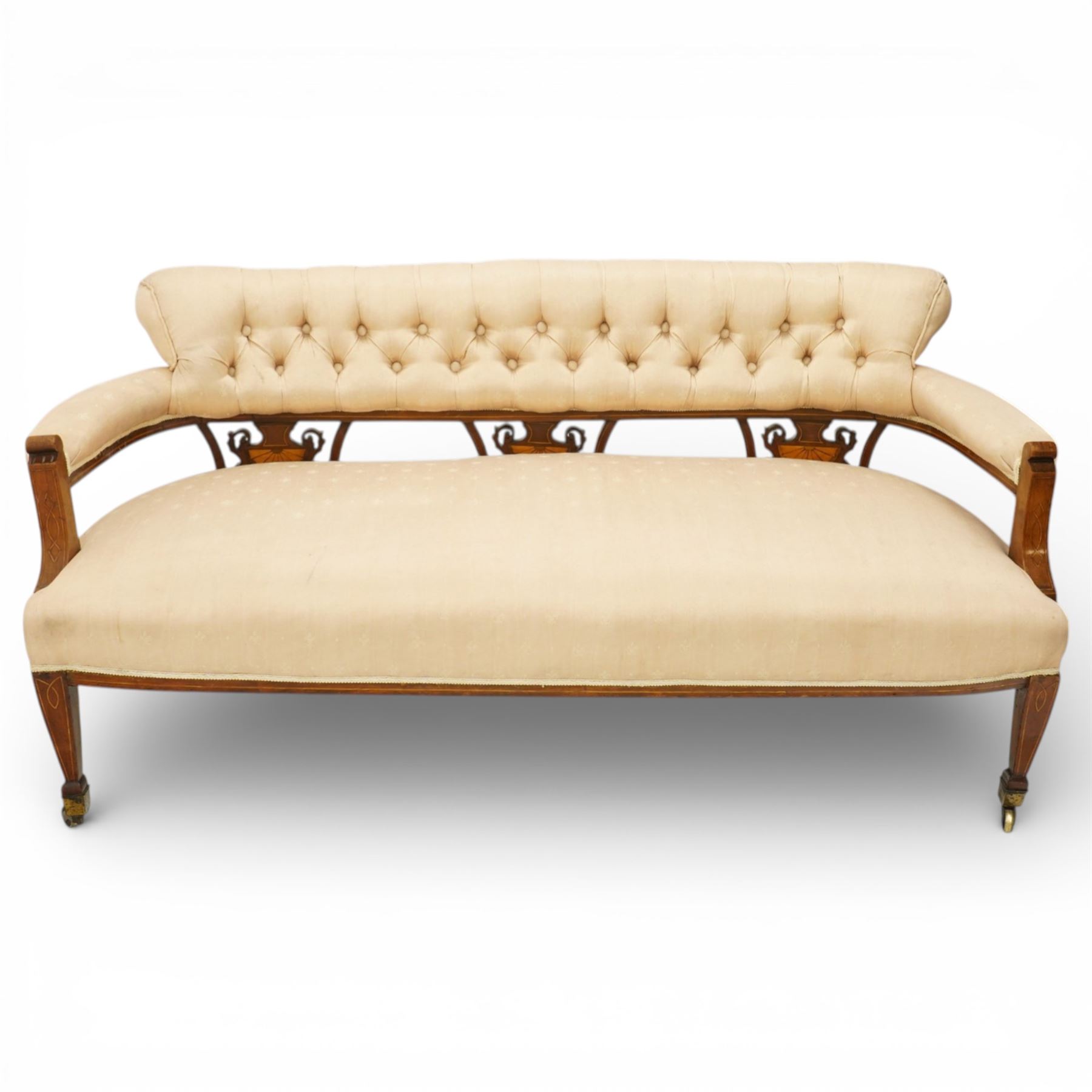Edwardian inlaid mahogany sofa, upholstered in cream fabric with buttoned back rail, tapering legs on brass castors