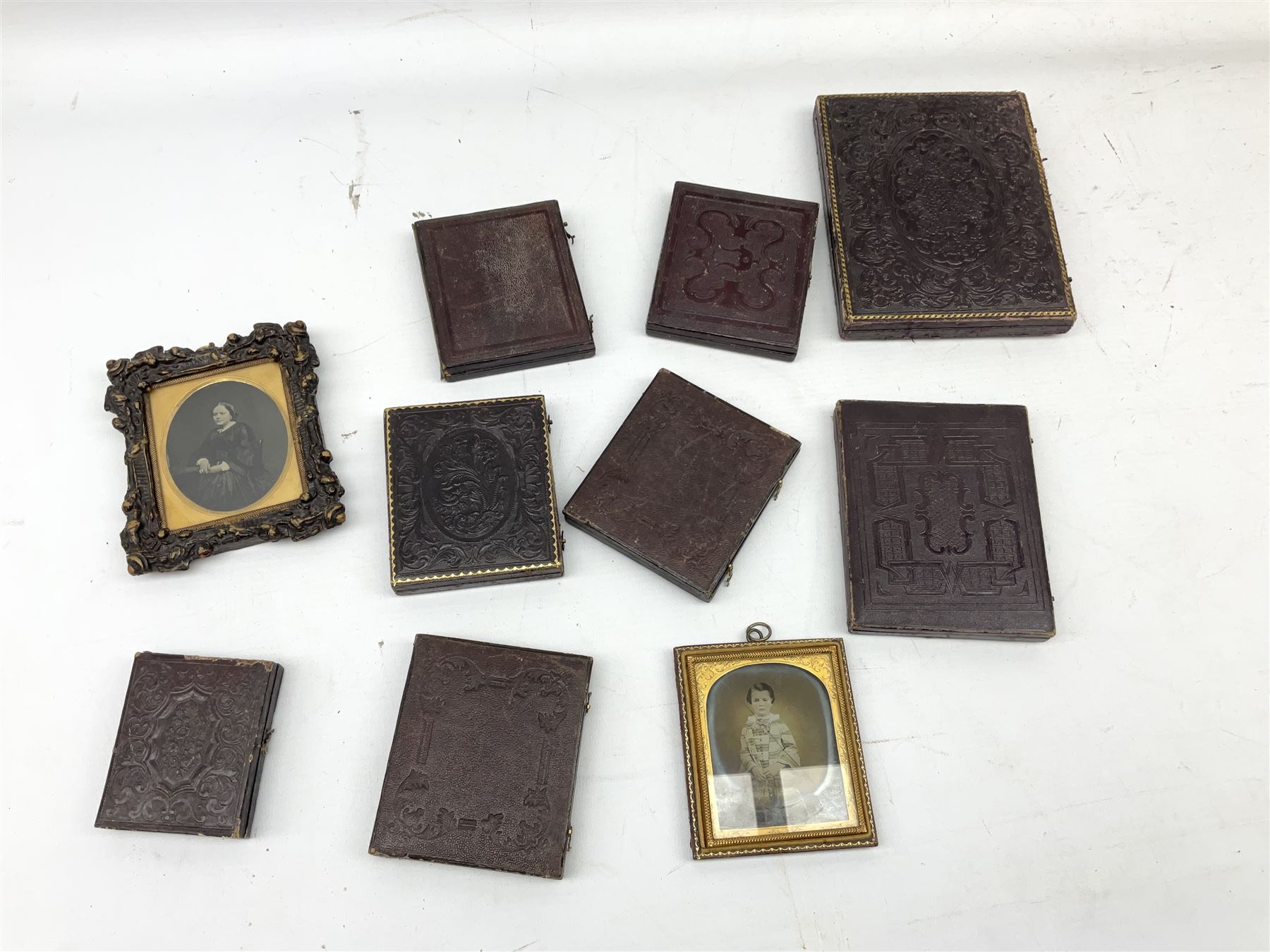 Collection of ten assorted Victorian daguerreotype, ambrotype and tintype portraits, most contained within leather cases with embossed red velvet or red silk lining, largest example with scrolling foliate embossed exterior H15cm when closed W12cm