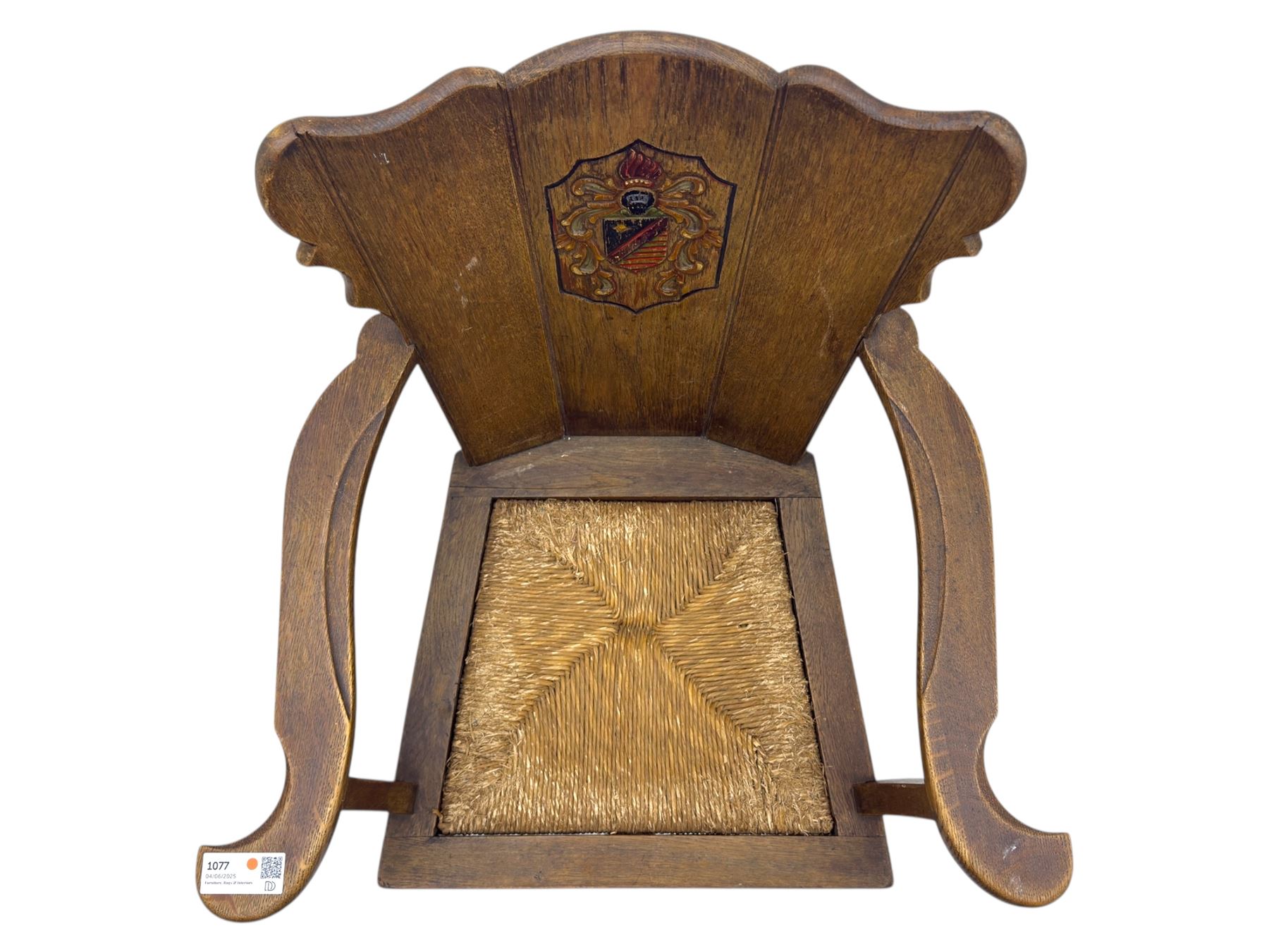 Pair of Arts and Crafts oak armchairs each with shaped backrest centred by polychrome painted crest, rush seat over straight square legs united by shaped central stretcher