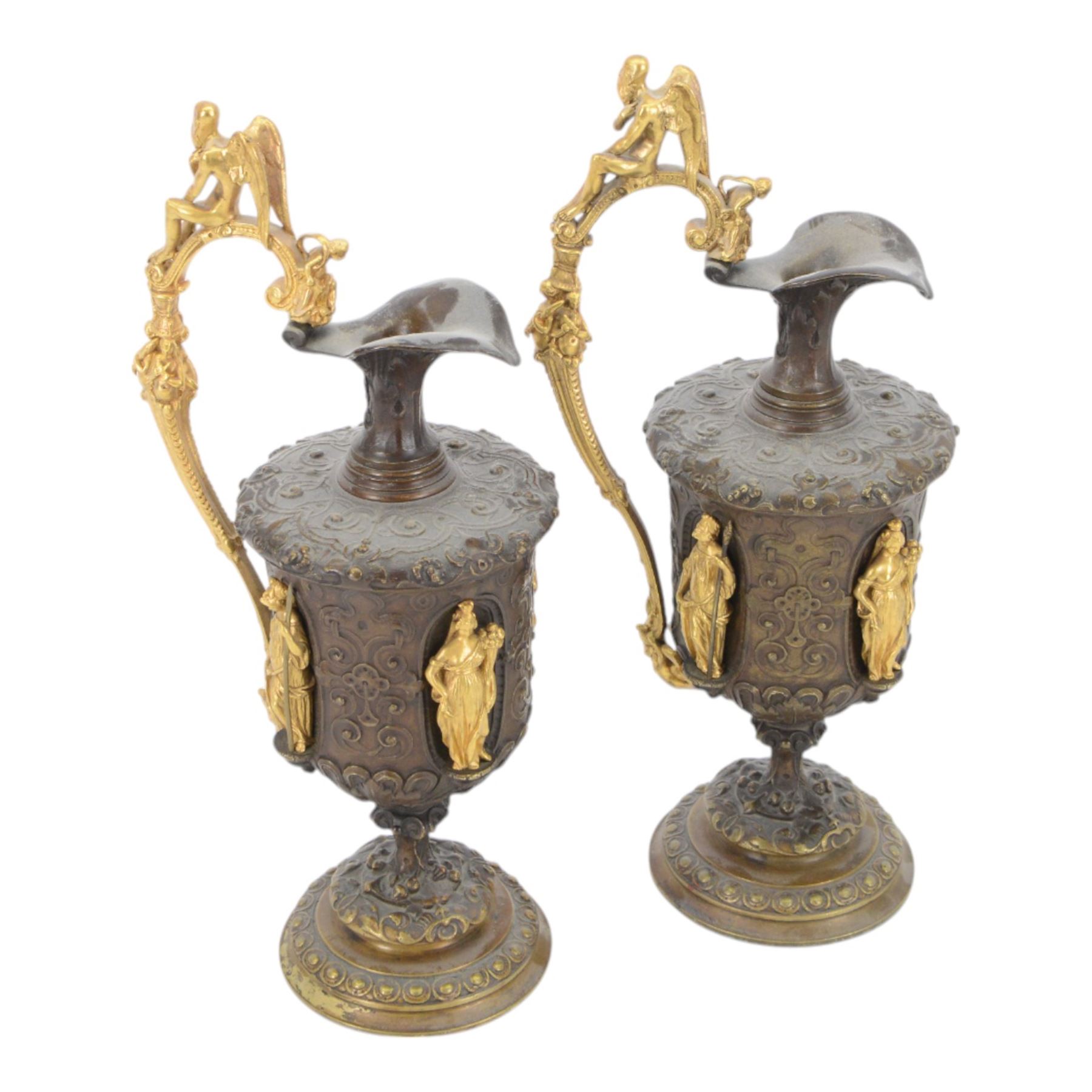 Pair of bronzed and gilt ewers in the Neo-Classical taste, each of typical form with figural detailed and mounted scroll handle surmounted by a winged figure, the bodies cast with scrolling strapwork, flower heads and acanthus leaves, and further detailed with applied gilt classical figures to oval recesses, upon a knopped stem and spreading circular foot with conforming cast detail, H28cm