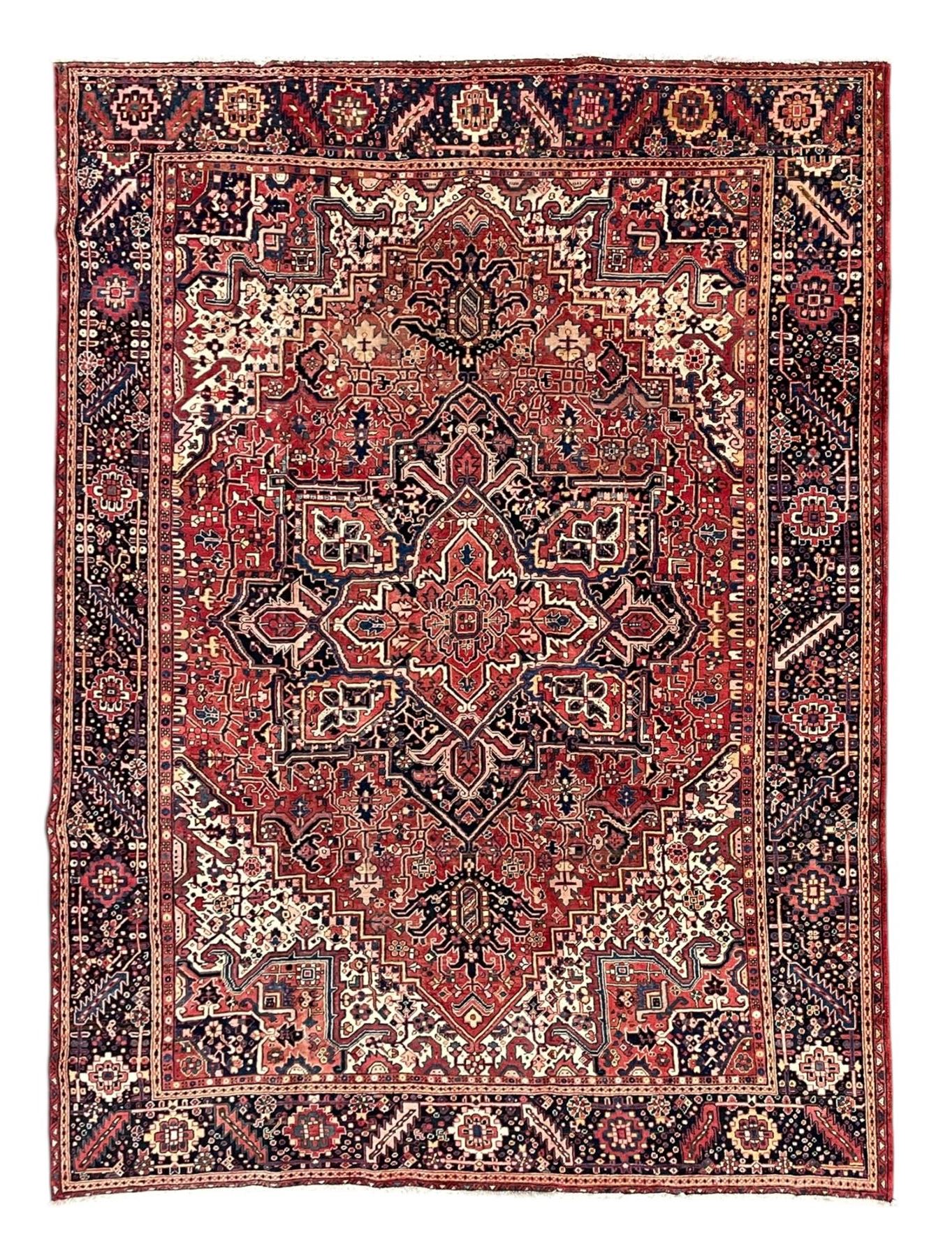 Persian Heriz crimson ground carpet, large central medallion comprising projecting palmettes with surrounding stylised plant motifs and trailing branches, the main border decorated with stylised leaf and flower head motifs within geometric pattern guard stripes