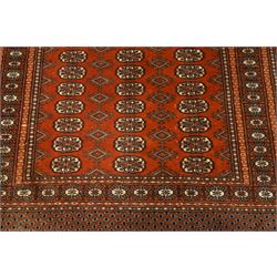 Bokhara hand-knotted carpet, terracotta ground with repeating rows of Tekke guls interspersed with geometric motifs, enclosed by multiple stylised floral and geometric borders, with fringed ends