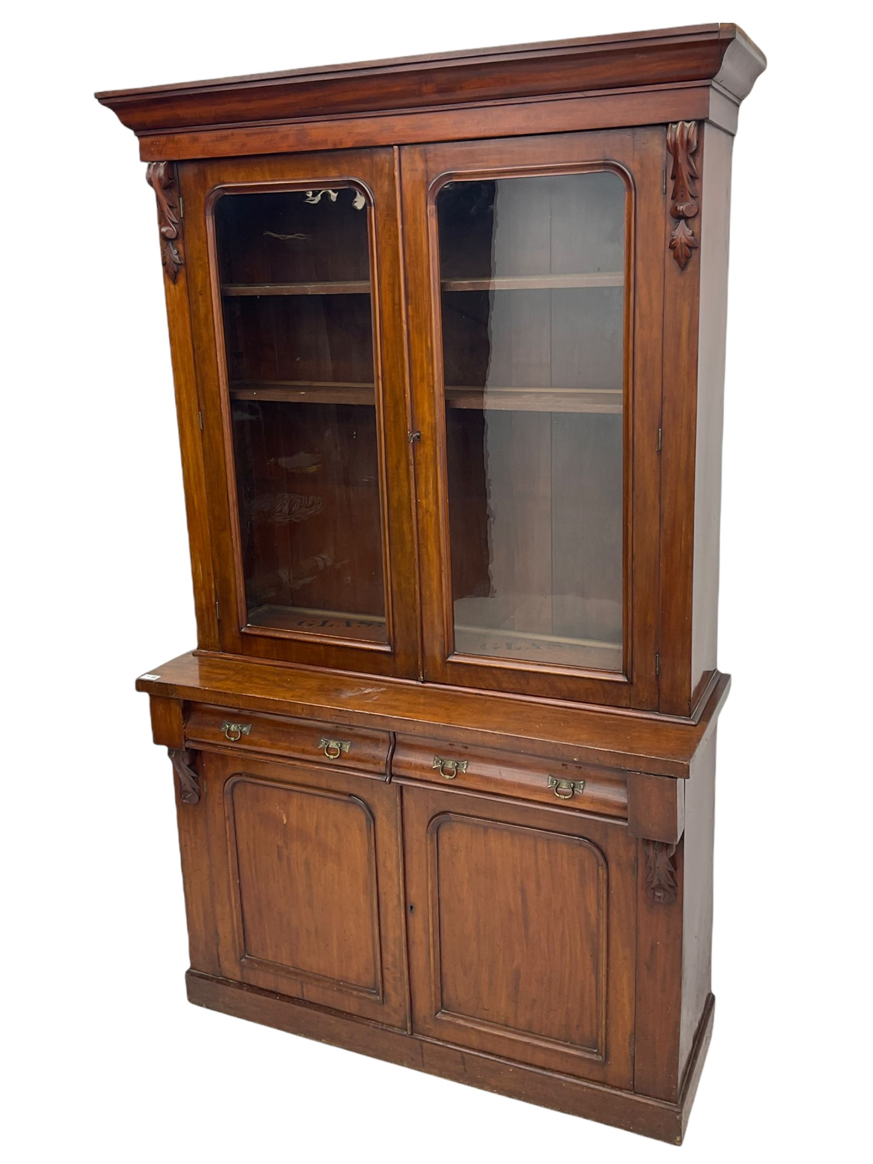 Victorian mahogany bookcase on cupboard, projecting cornice over two glazed doors and carved corbels, fitted with two drawers and double cupboard, plinth base