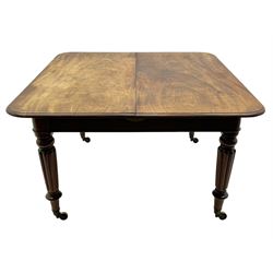 Early 19th century figured mahogany extending dining table, the rectangular top with moulded edge and rounded corners, pull-out action with three additional leaves, raised on turned and lobe carved supports with brass cup castors