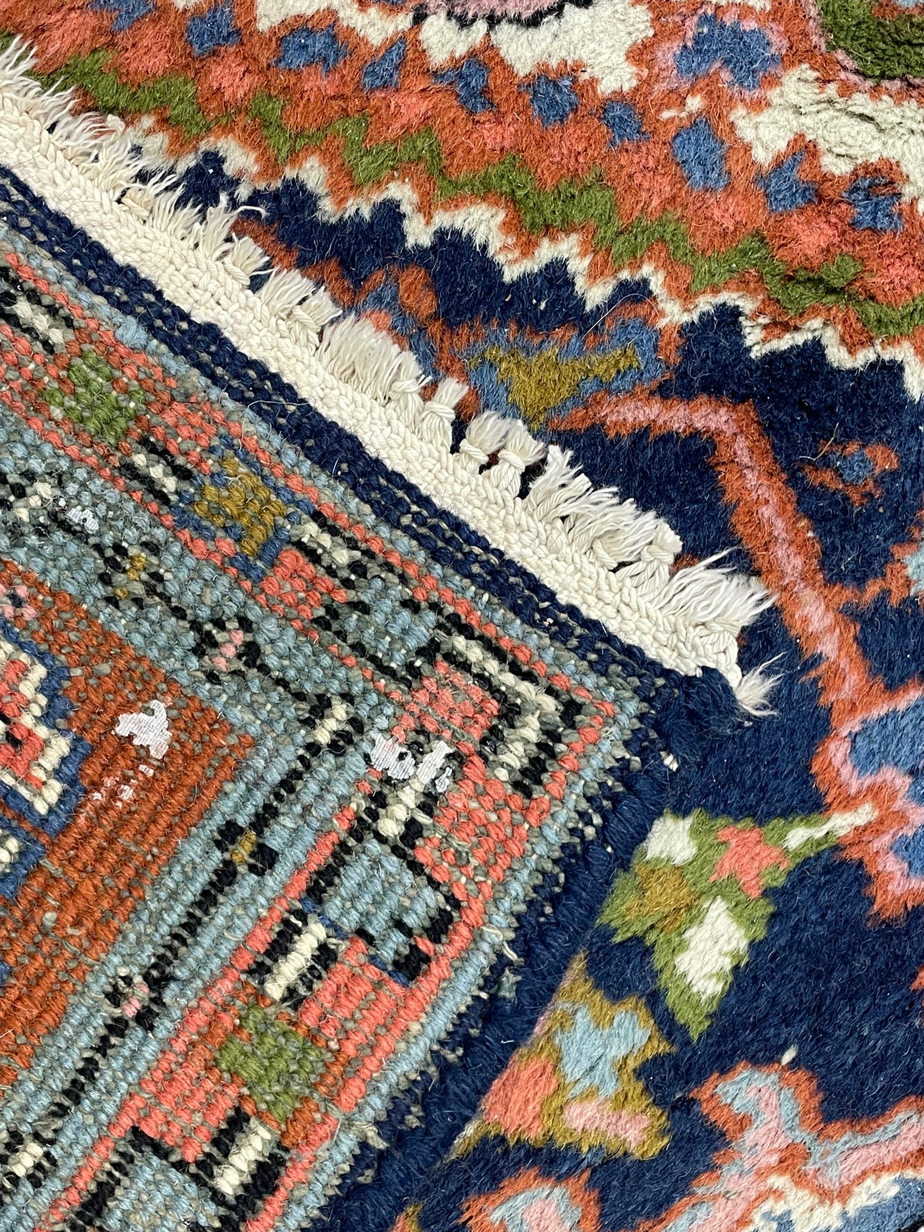 Persian Heriz indigo and rust ground rug, central geometric star medallion decorated with stylised foliate motifs, the border decorated with stylised flower heads