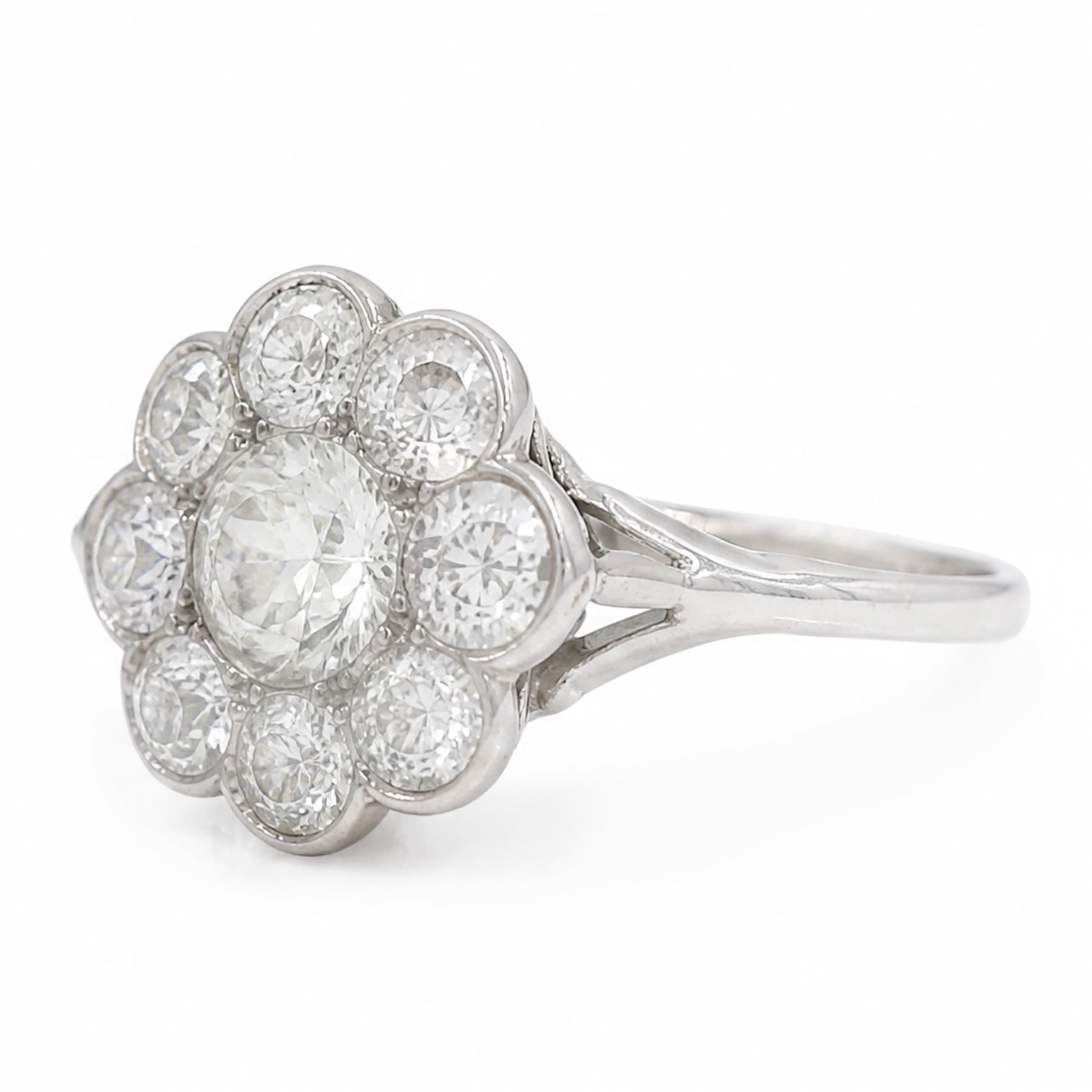 Early 20th century platinum diamond daisy flower head cluster ring, principal round cut diamond of approx 0.65 carat, surrounded by eight milgrain set old cut diamonds, within a pierced scroll design gallery, total diamond weight approx 2.15 carat