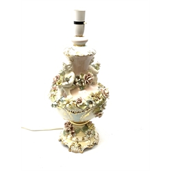 A Italian Capodimonte style lamp base, of pedestal urn form with applied putti and encrusted flower detail, heightened with gilt, overall H46cm. 