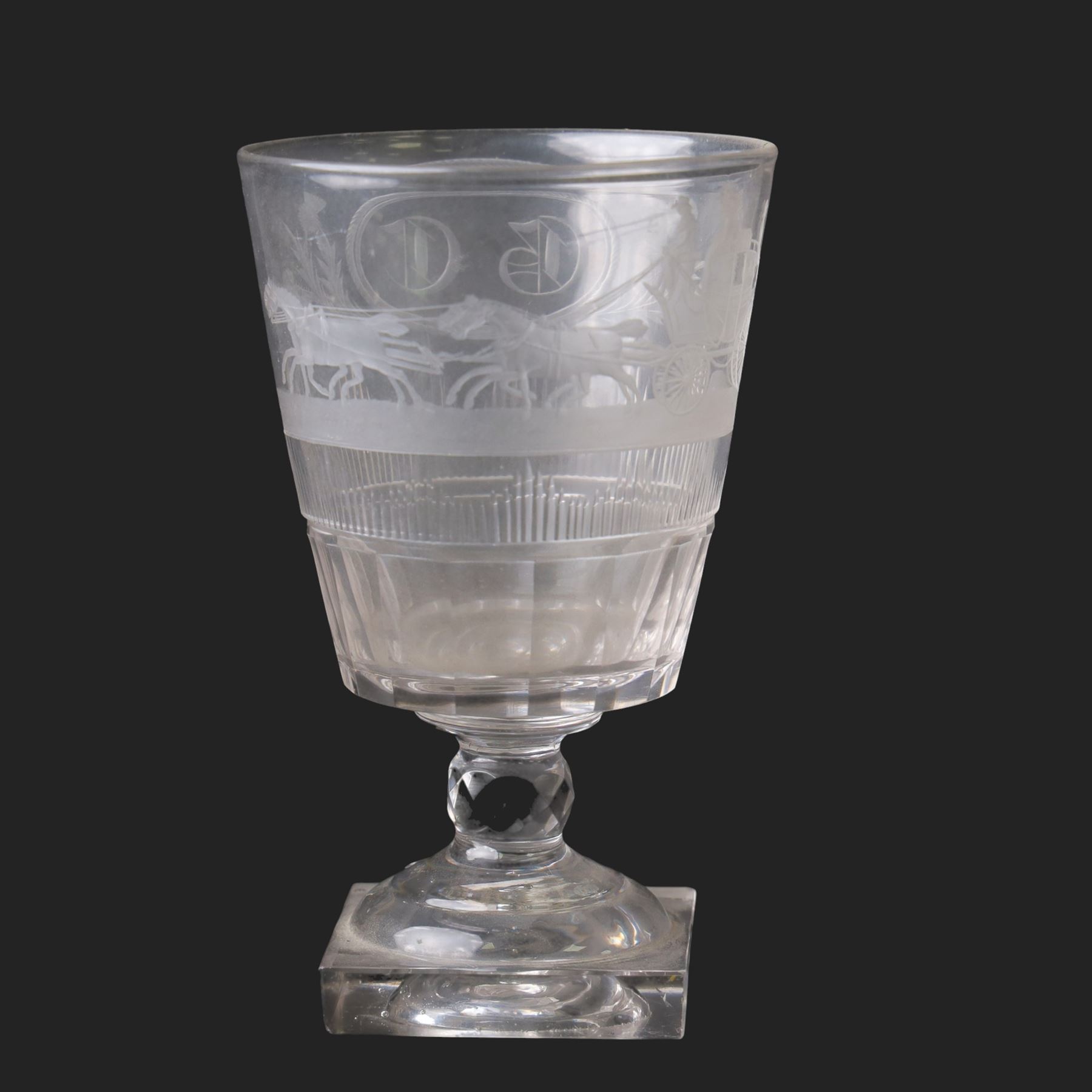 Early 19th century glass rummer, the deep bucket shaped bowl engraved with an oval roundel containing initials BC flanked by flowers of the Union, and a carriage drawn by four horses, above cut fluted and vertical cut bands, upon a short diamond cut knop stem, and square base, H15cm