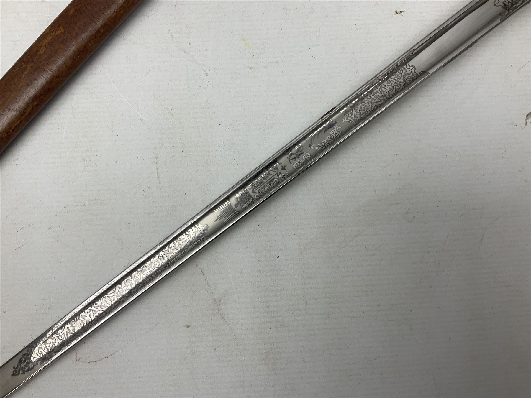 George V 1897 pattern Army Officer's sword by Henry Wilkinson Pall Mall London, the 82.5cm 'London Made' blade etched to both sides with Royal Crests and cyphers etc, pierced half-basket hilt with wire-bound fish skin grip and remains of leather knot strap; in leather covered field service scabbard L101cm overall; and two 14th Prince of Wales Own swagger sticks (3)