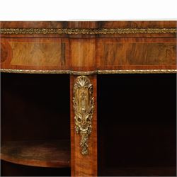 Late Victorian figured walnut credenza, the shaped demi-lune top with cross-banding and stringing over an inlaid frieze with foliate gilt-metal mounts, fitted with a central geometric-inlaid panelled door, flanked by convex-glazed side-cabinets with a gilt metal slip and outer-banding, the uprights surmounted by gilt-metal cartouche mounts with cascading foliage details, raised on a shaped skirted base with central female-mask gilt mount