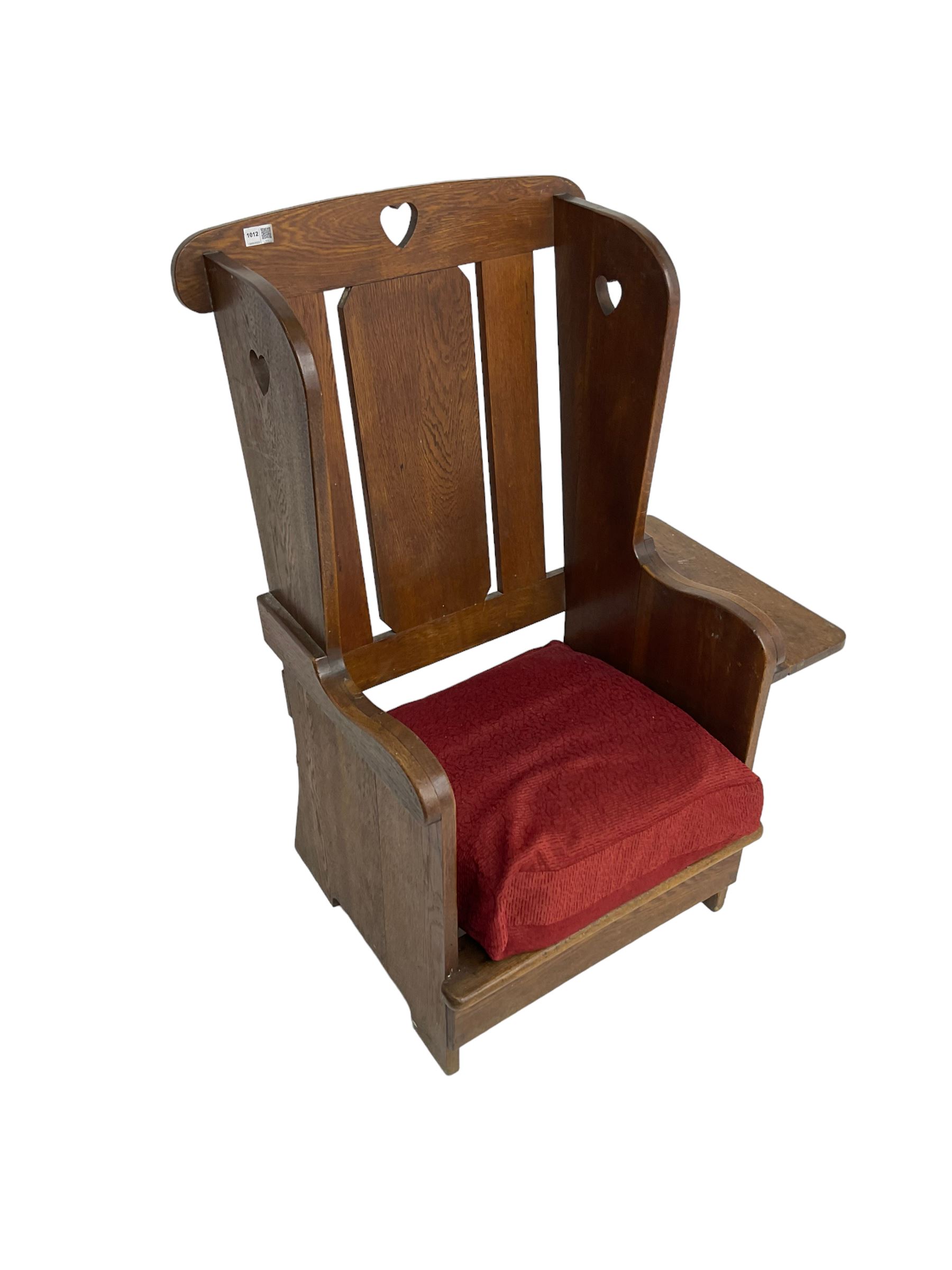 Arts and Crafts design oak reading wingback armchair, high back with pierced heart design, drop-leaf side table to one arm