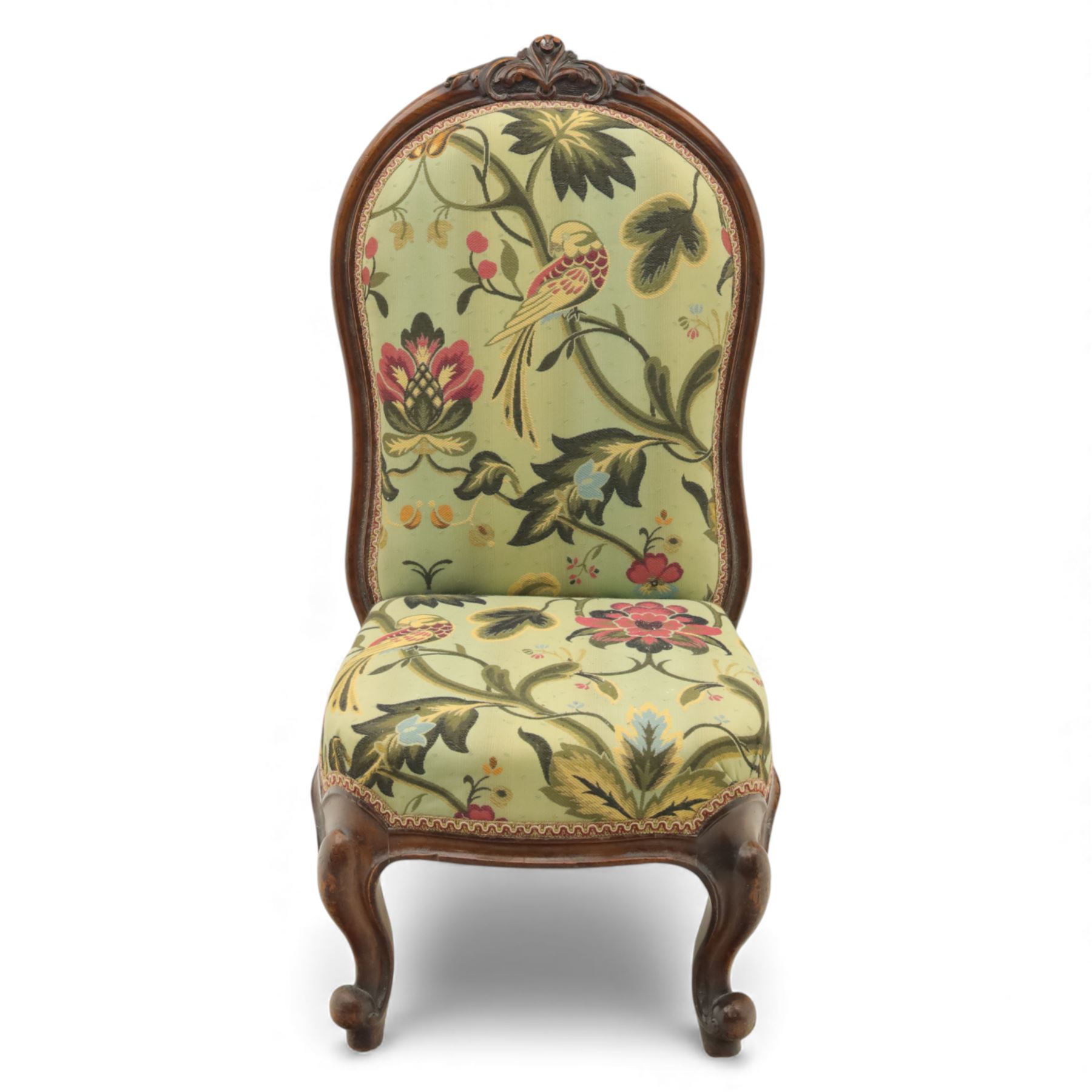 Small Victorian mahogany nursing chair, with carved top rail above a padded balloon back and shaped seat upholstered in light green fabric detailed with exotic birds and flowering vines, raised upon cabriole front legs and turned rear supports