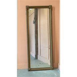 Edwardian giltwood and composition framed upright wall mirror, having a floral boss to eac...