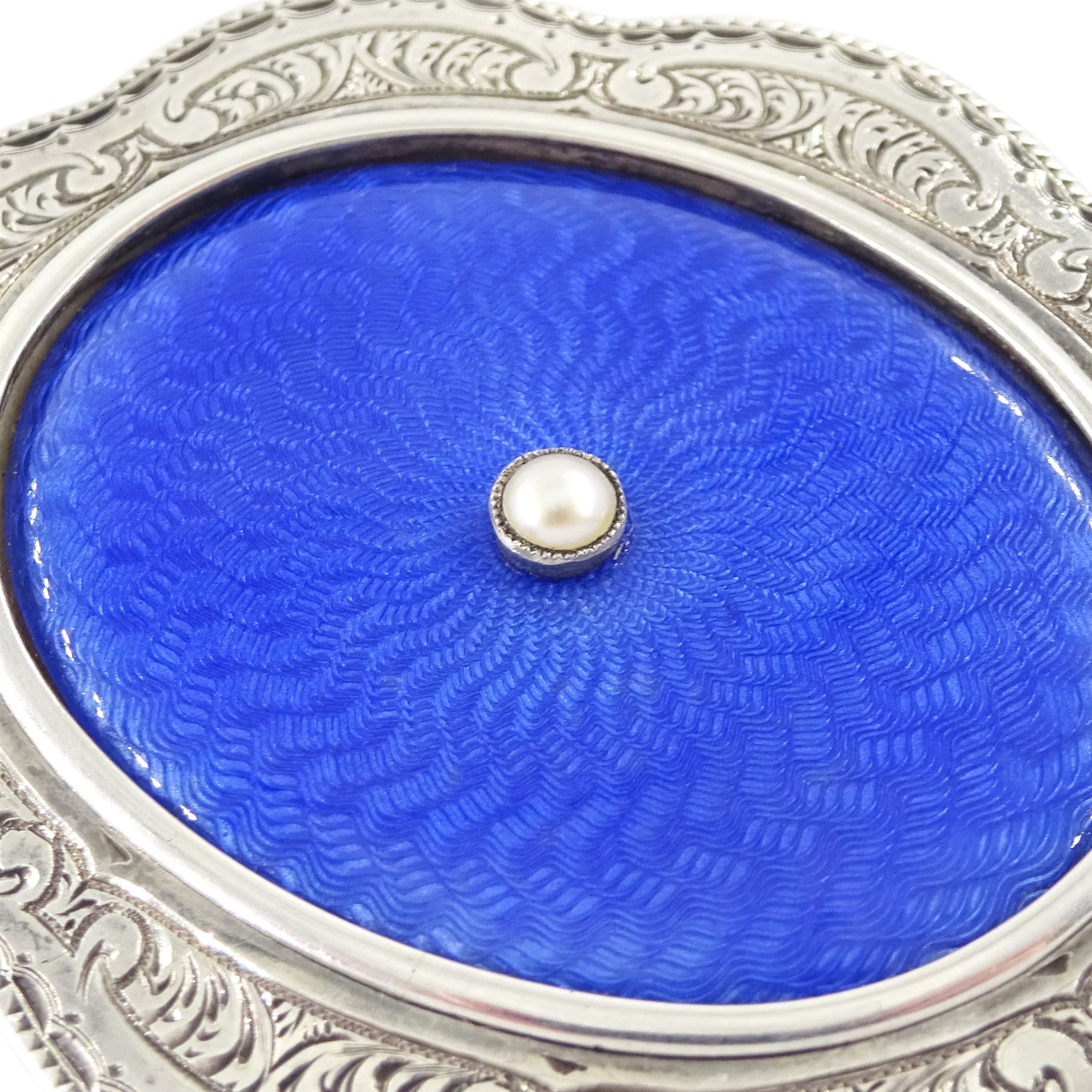 Early 20th century silver guilloche enamel portrait pendant, set with an oval miniature of a gentleman wearing a grey suit on ivory, within a blue enamel and marcasite border, the reverse set with a blue enamel panel and single split pearl, within a silver engraved border, suspended from a marcasite bail

This lot has been registered for sale under Section 10 of the APHA Ivory Act