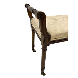 George III style walnut duet piano stool, scrolled supports with flower head carved terminals, on turned supports with brass cups and castors