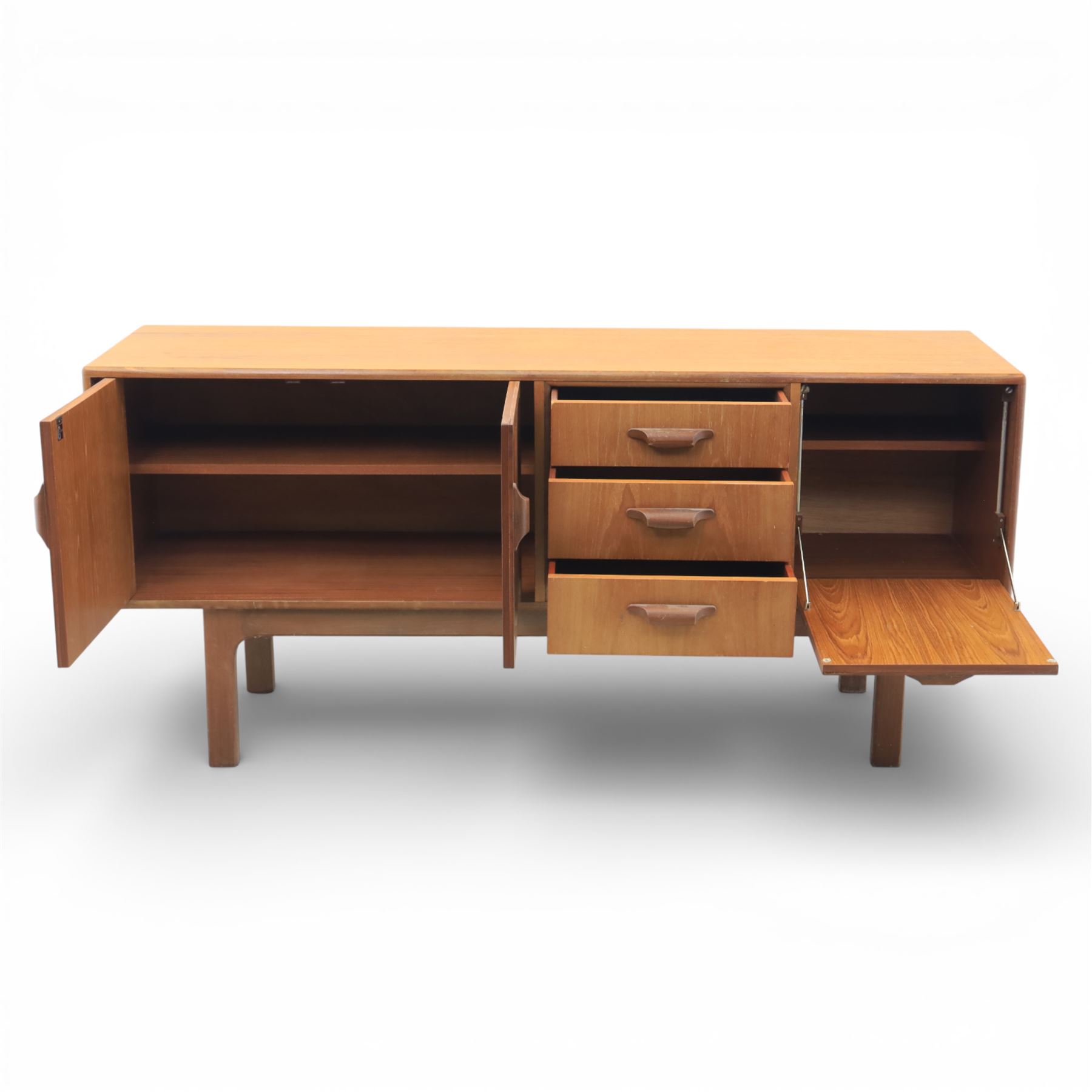 G-Plan - ‘Brasilia’ teak sideboard, rectangular top with moulded edge above a central bank of four drawers flanked by cupboard doors with carved sculptural handles, raised on tapering supports
