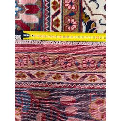 Northwestern Persian Lillihan hand-knotted carpet, madder red field with scrolling vines, rosettes, and palmettes around a central circular medallion in navy, ivory and ochre, and ivory ground spandrels within a navy border of stylized flowerheads and vines between multiple guard stripes 