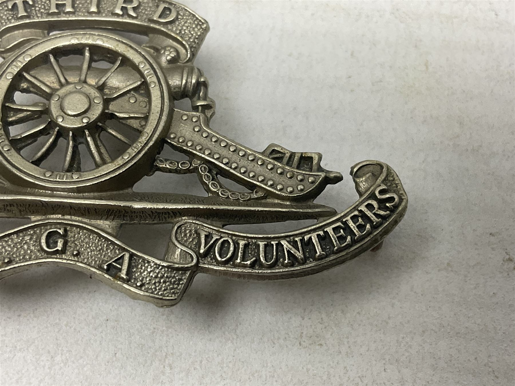 Third Middlesex Royal Garrison Artillery Volunteers Cap Badge, white meta Royal Artillery cap badge with “THIRD” to the top scroll and lower three part scroll “MIDDLESEX – R.G.A. – VOLUNTEERS”. Three lug fittings to the reverse.