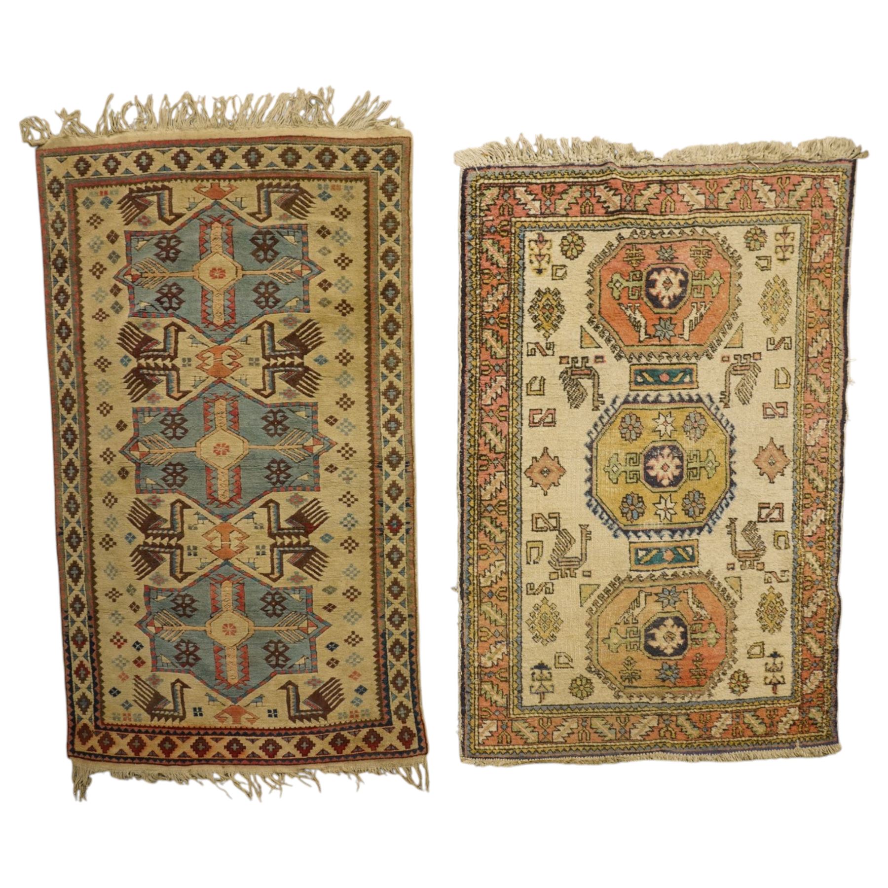 Two Caucasian designed rugs comprising a flatweave and hand-knotted rug, Caucasian design flatweave, cream ground with three large blue geometric medallions surrounded by stylised birds and geometric motifs, enclosed by repeating geometric border, fringed ends, H176cm, W102cm; hand-knotted Caucasian rug, ivory ground with three polychrome octagonal medallions surrounded by stylised animals, flowerheads and geometric motifs, enclosed by salmon pink geometric border, fringed ends, H163cm, W106cm
