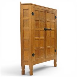 Mouseman - 1940's adzed and panelled oak corner cupboard, the raised quarter-gallery back over twin adzed panelled doors with wrought iron fittings and latch, enclosing three shaped shelves, raised on turned octagonal supports, with carved mouse signature in relief, by the workshop of Robert Thompson of Kilburn Provenance: purchased directly from the Kilburn workshop in the late 1940s
