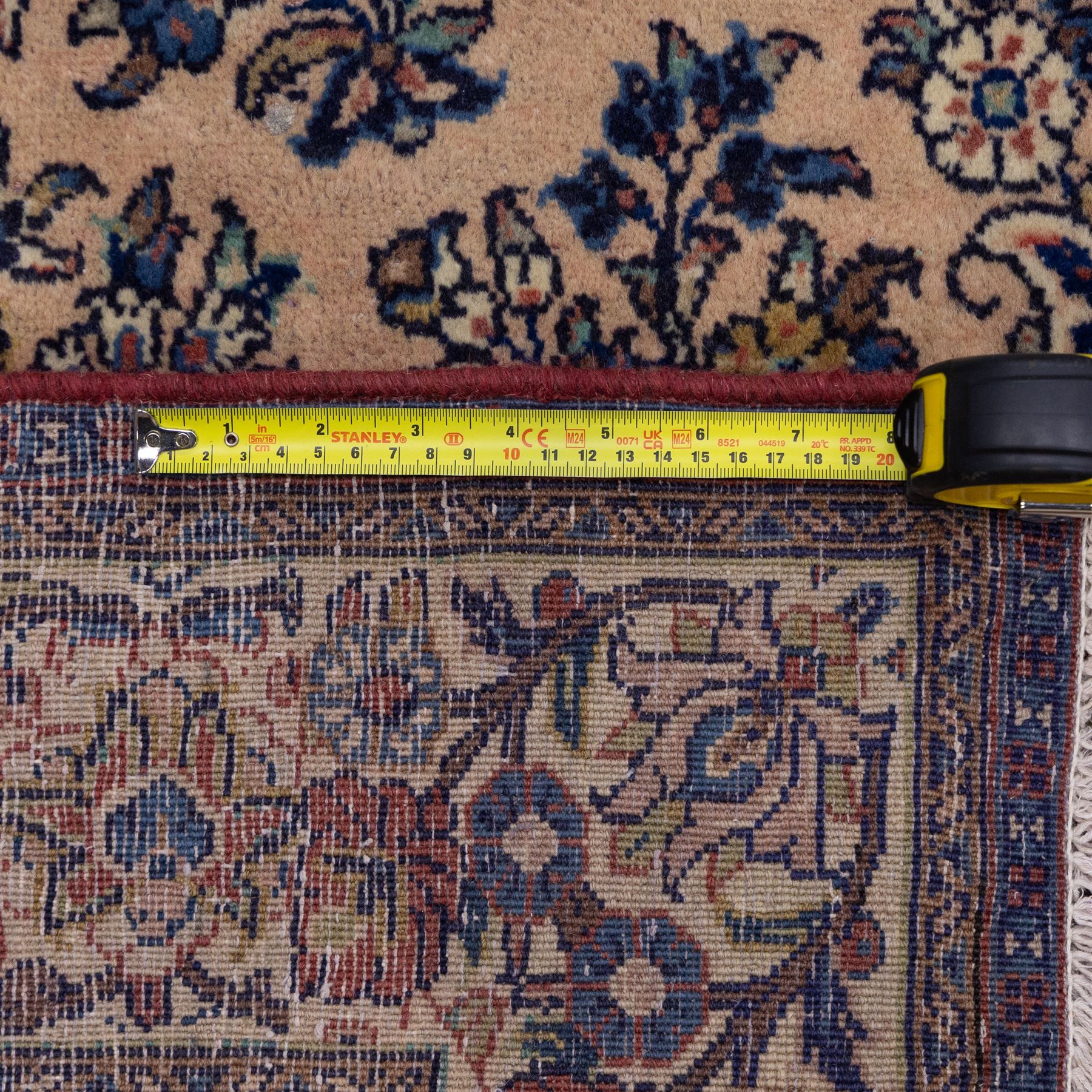 Central Persian Nain hand-knotted rug, ivory ground decorated with a central lobbed medallion and an all-over floral and foliate design of stylised palmettes, flowering plants, and scrolling vine work, enclosed by a contrasting main border with repeating floral motifs, flanked by multiple guard borders, with cotton fringe ends 