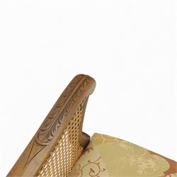 Pair of mid-20th century mahogany framed bergère armchairs, each with carved scroll arms and caned side panels, floral upholstered loose cushions, raised on cabriole front supports