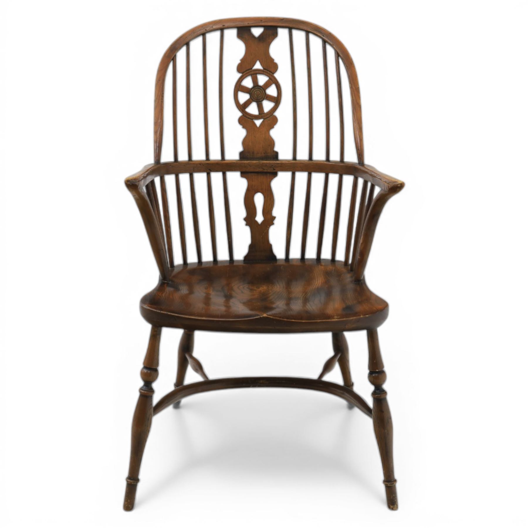 Late 19th century stained elm and beech Windsor armchair, the arched hoop back with pierced wheel splat above shaped lower splat between turned spindles, shaped arm rail on turned supports, saddle seat, raised on turned legs united by a crinoline stretcher