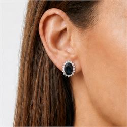 Pair of 18ct white gold sapphire and diamond cluster earrings, each stud set with a single oval cut sapphire, surrounded by sixteen round brilliant cut diamonds, total sapphire weight approx 6.65 carat, total diamond weight approx 1.00 carat