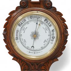 Edwardian-aneroid barometer in a carved oak case with an 8” porcelain register, steel indicating hand and brass recording hand, with a surface mounted mercury thermometer recording the temperature in degrees Fahrenheit and Celsius.
