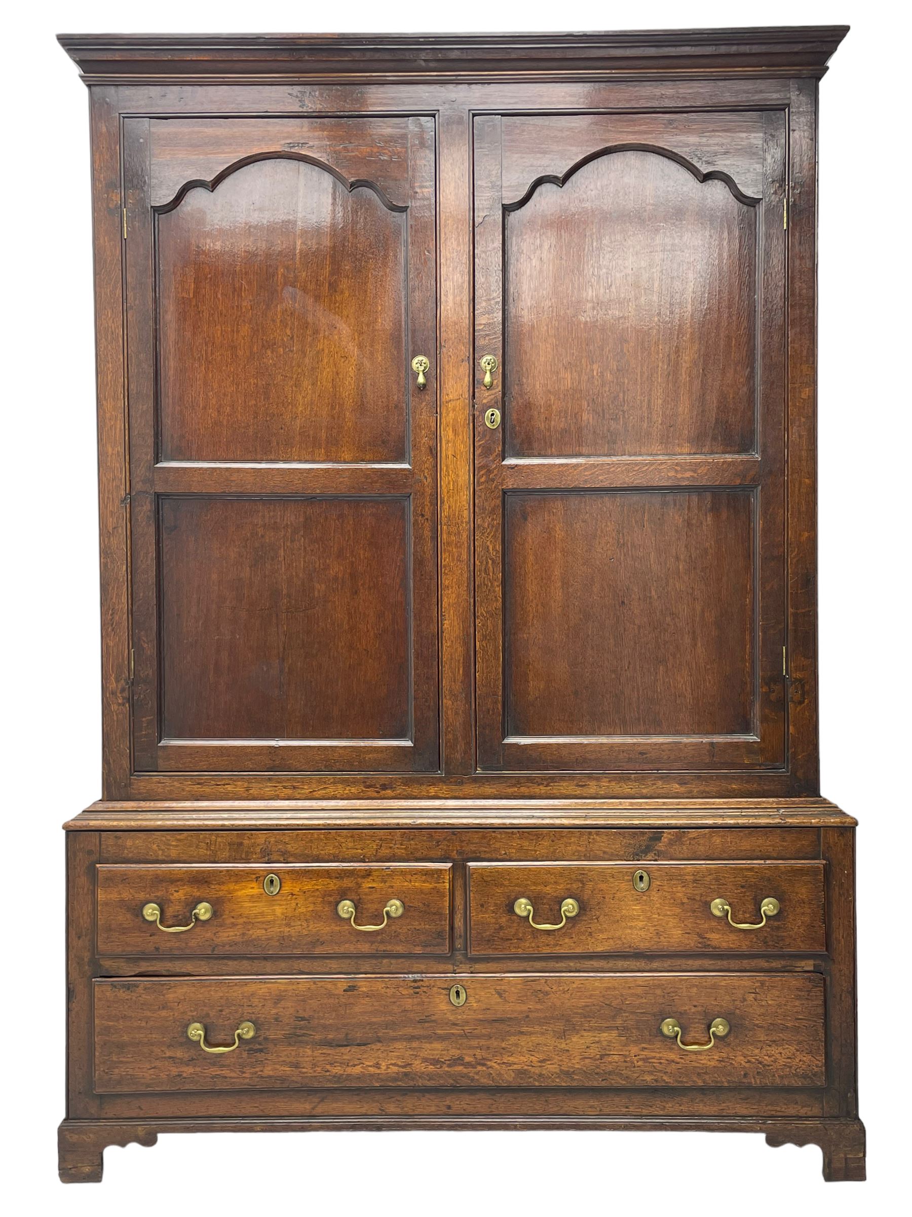 George III oak livery cupboard, projecting moulded cornice over two panelled doors, the upper panels within stepped ogee and arched moulded frame, the interior fitted with a single row of wooden hooks, two short and one long drawers, on bracket and return skirted base 