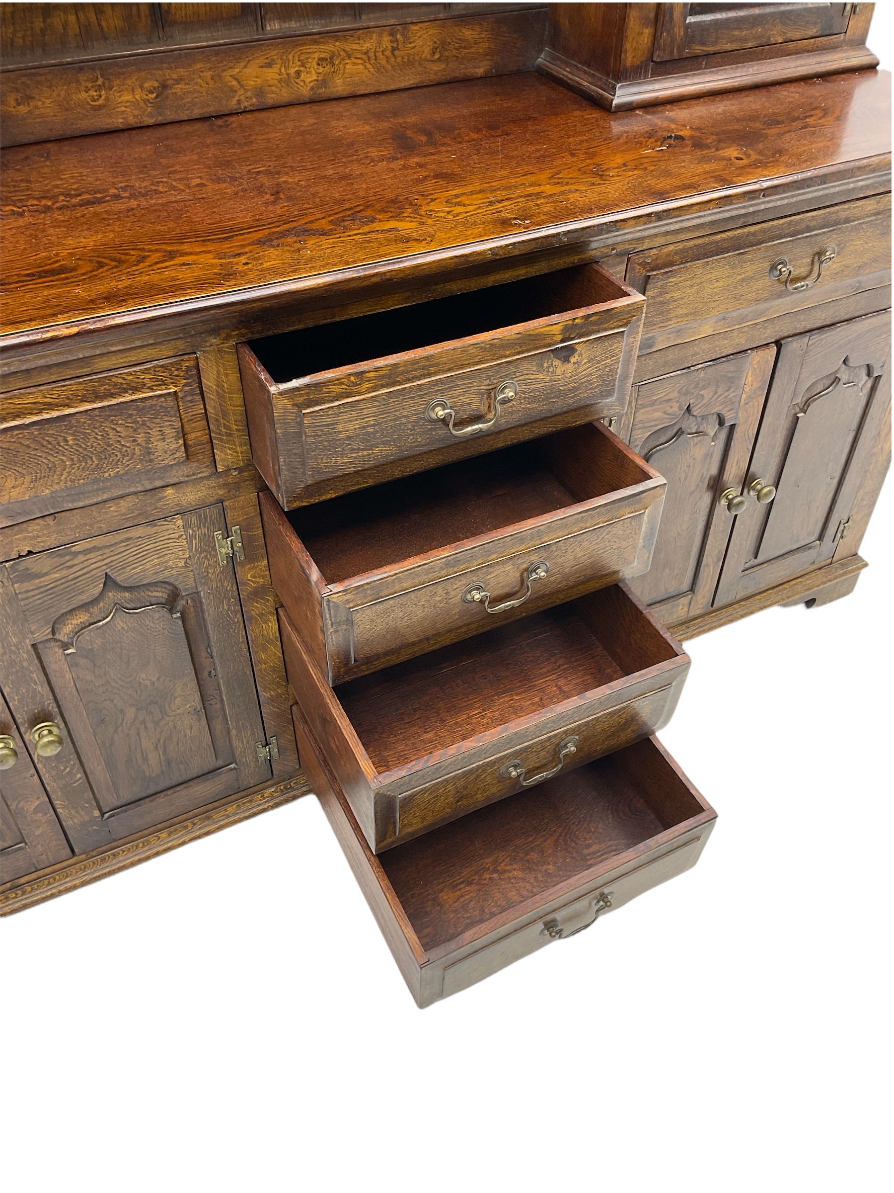 Traditional oak dresser, the moulded cornice over shaped apron, three heights plate rack fitted with two cupboards, the base fitted with six drawers and two double cupboards, panelled pointed ogee arched doors, on bracket feet
