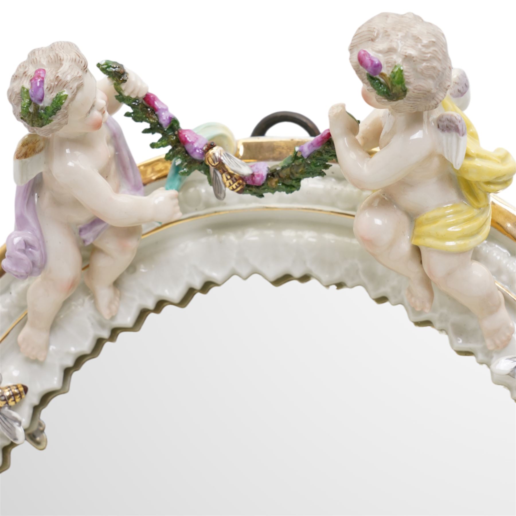 Sitzendorf oval table mirror with two cherubs holding a floral garland above foliage and insects etc on easel stand 40cm x 31cm