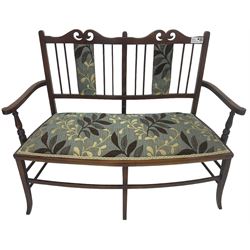 Edwardian stained beech framed two-seat settee, shaped cresting rail with pierced decoration, upholstered in leaf patterned fabric, on square tapering supports with splayed feet