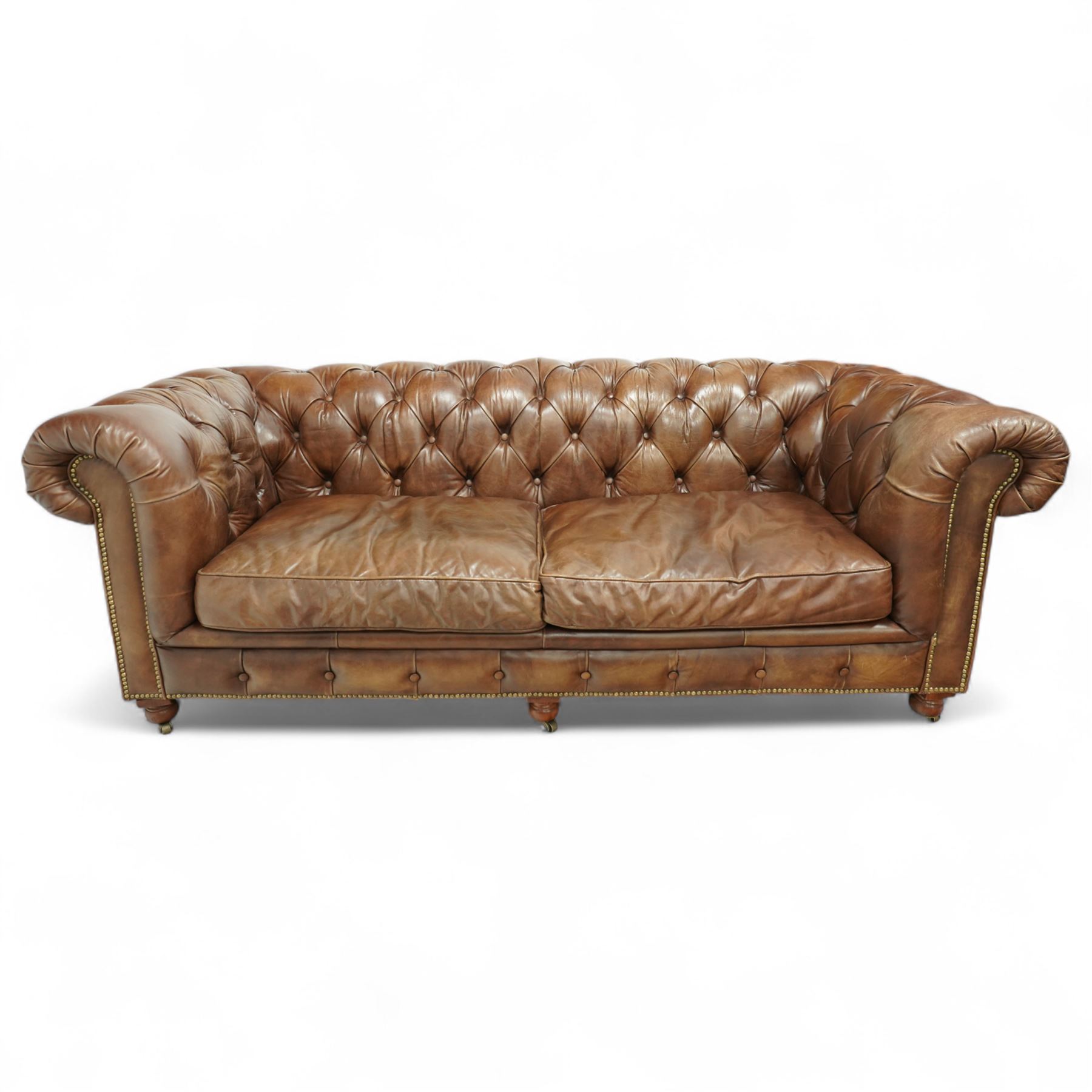 Timothy Oulton, Halo - late 20th century brown leather Chesterfield settee, the upholstered frame with deep buttoning to back and arms, large scroll terminals with brass studwork, twin seat cushions, raised on castored legs