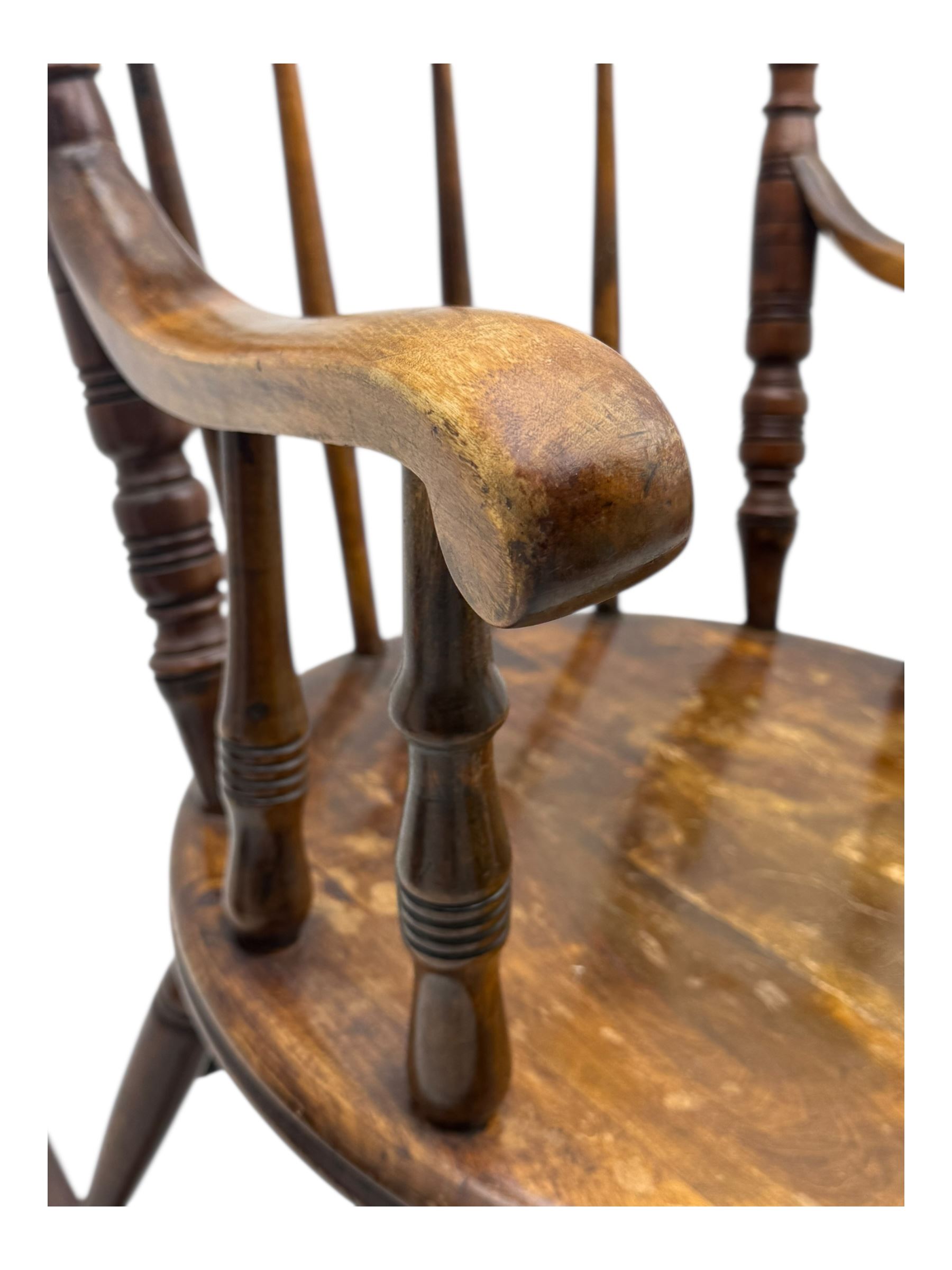 Late 19th century elm and beech Windsor rocking chair, with shaped top rail over turned spindles and curved arms, circular seat raised on turned legs united by stretcher on rockers
