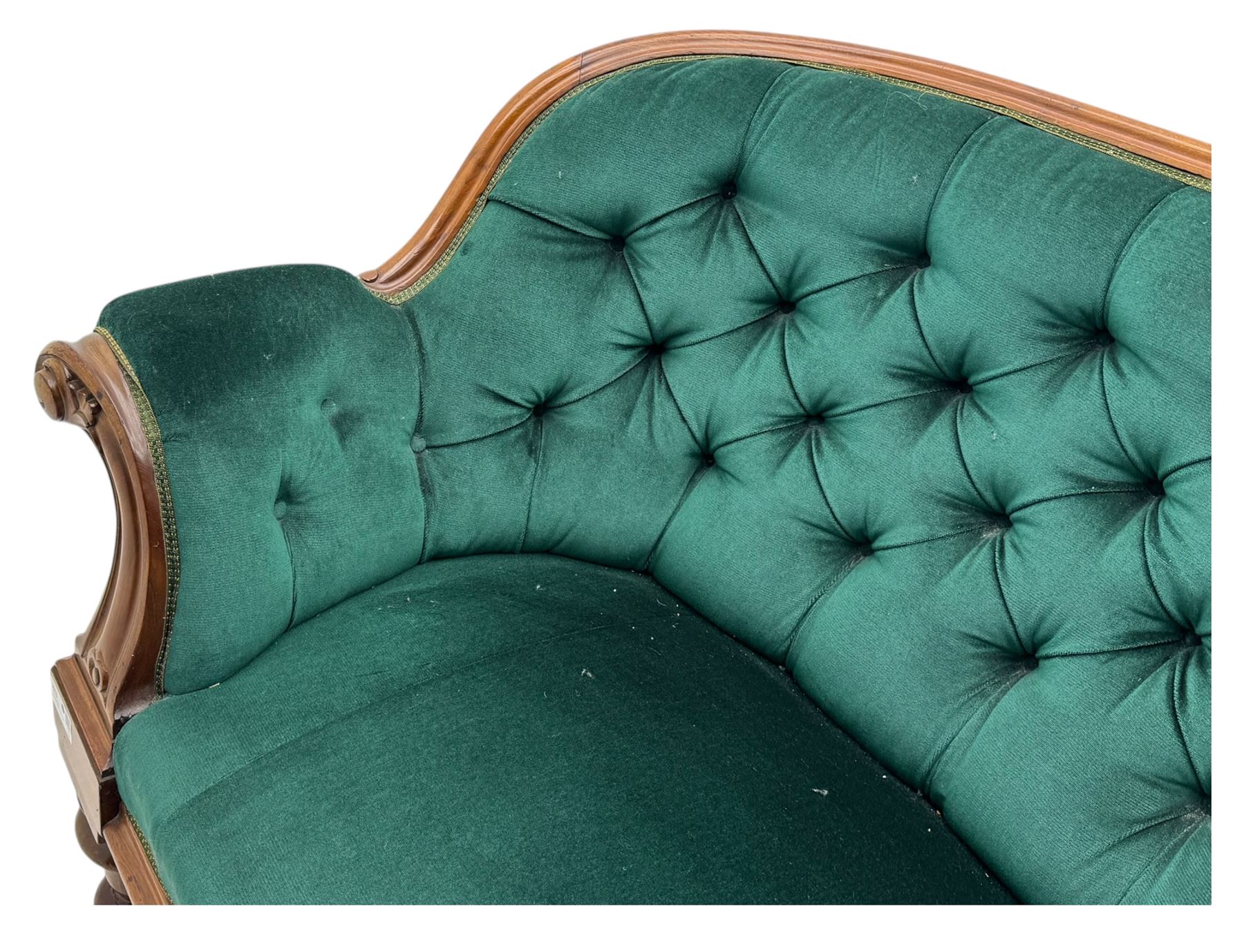 Victorian mahogany settee, upholstered in green buttoned fabric, moulded frame and scroll carved arm terminals, turned supports on castors