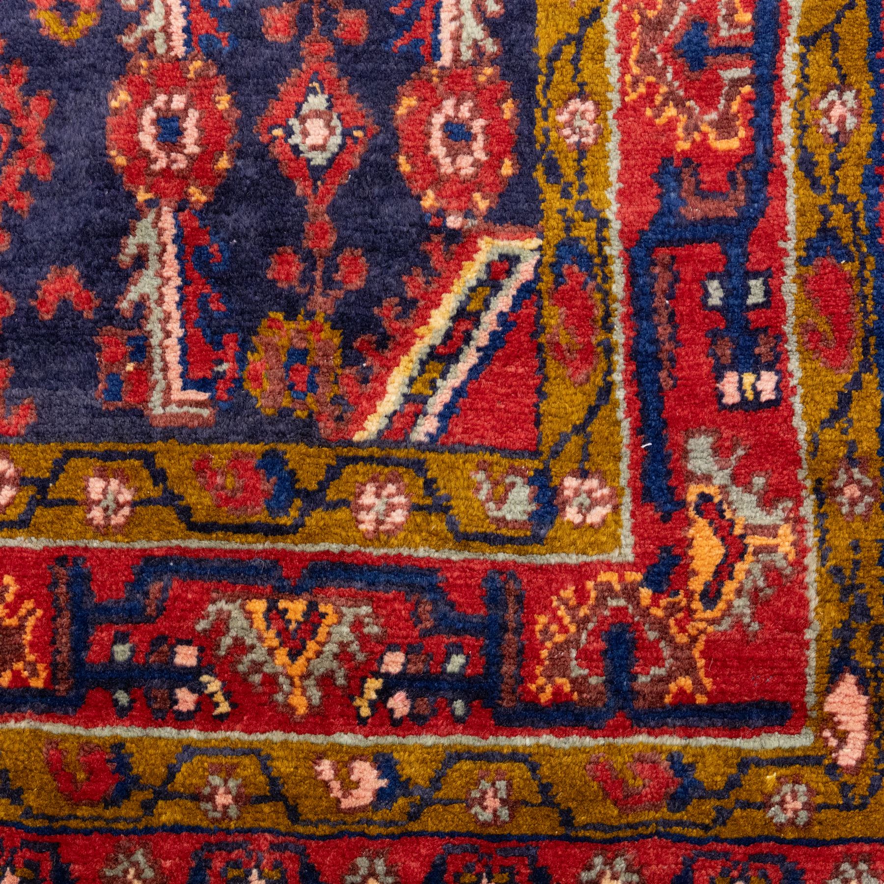 North West Persian Cirjan hand-knotted rug, indigo field decorated with vertical columns of stylized boteh, rosettes and diamond devices arranged in a repeating lattice and a chain of linked lozenges, enclosed by a mustard gold inner border and a principal border of madder ground, flanked by narrow guard stripes, with cotton fringe ends 