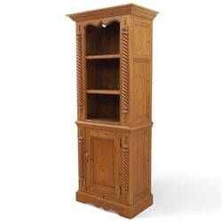 Contemporary stripped pine bookcase cabinet, the upper section with arched frieze and open shelving flanked by barley twist columns, over a single door cupboard base with matching twist supports and fielded panel door