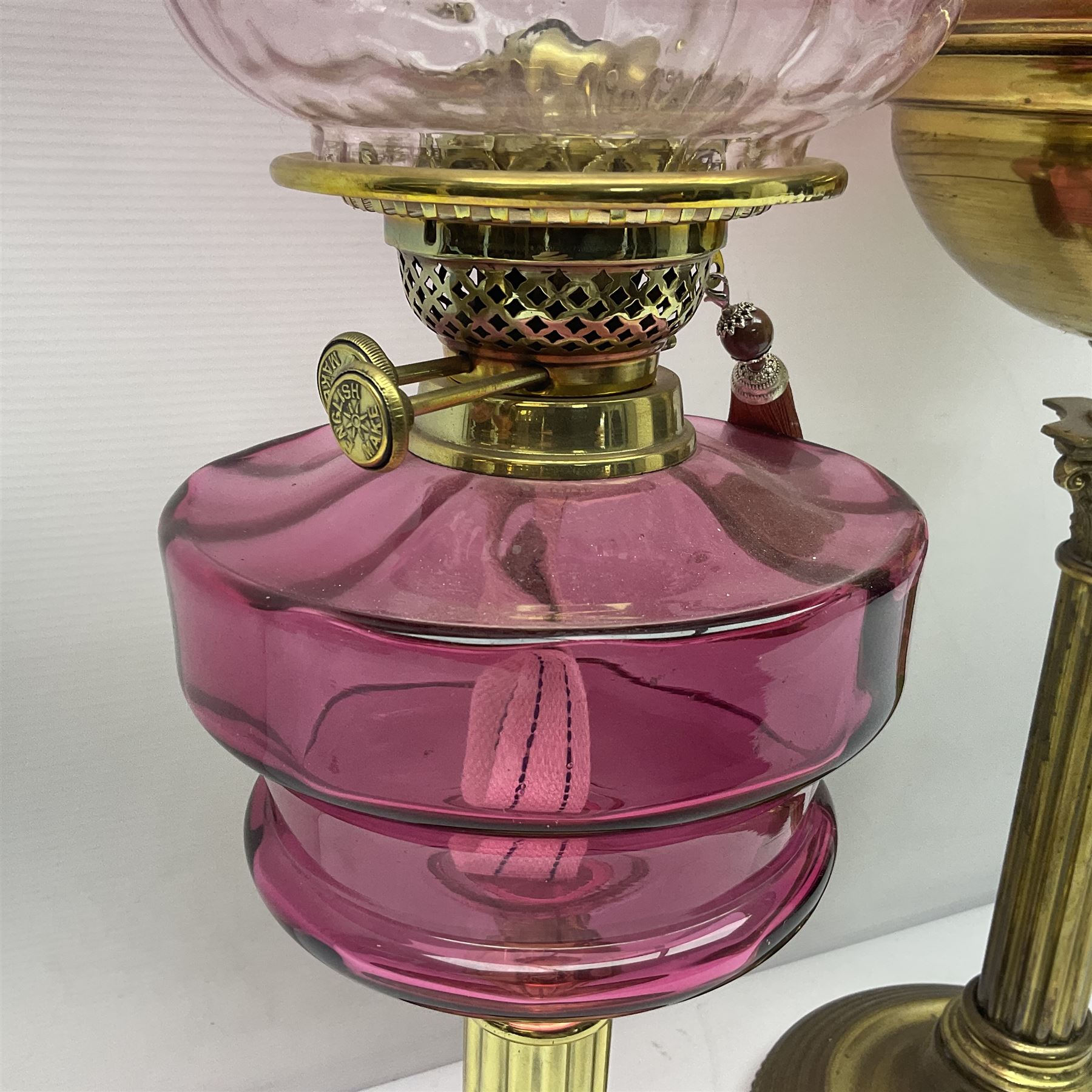 Victorian cast brass oil lamp, with fluted pink glass shade, together with two smaller brass oil lamps with pink shades and reservoirs and a pair of oil lamps, the bases modelled as putti, with pink glass reservoir  and frosted shades, tallest H70cm