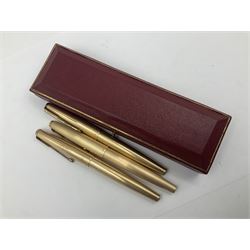 Three rolled gold Parker fountain pens, comprising an example with a gold nib marked 14K 585 and barrel with a shell stamp, a Parker 61 fountain pen with inset gold arrow to the nib, and another similar, all with striated decoration and arrow clips to the caps, L13cm, one with box